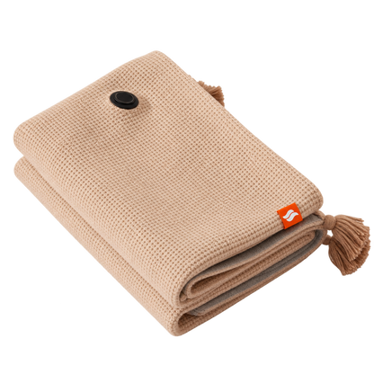 Thermapulse CozyWrap beige folded USB heated blanket with tassels and round control on a transparent background.